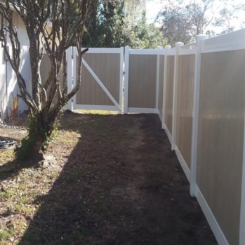 Tan colored vinyl fencing with white accent on the side yard of a house
